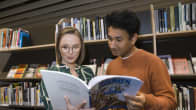 A man and a woman reading a book in a library.