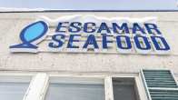 Escamar Seafood -yrityksen kyltti talon seinässä.