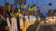 Ukrainan lippuja pitelevät ihmiset seisovat kadulla.