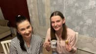 Alina Vinichenko ja Nataliia  Bystrytska syövät pullaa punaliinaisen pöydän ääressä.