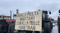 Traktori, jonka keulaan kiinnitetty mielenosoituskyltti, jossa lukee "Kauhalla meiltä vaaditaan, lusikalla meille annetaan".