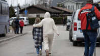 (From behind) an adult walks down the street with their arm around a child outside Vantaa's Jokiranta teaching site.