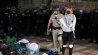 Poliisi saattaa nuorta naista käsiraudoissa pois mielenosoituksesta UCLA-kampuksella.