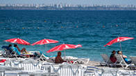 Aurinkoranta ja turisteja rannalla varjojen alla Turkissa Antalyassa.