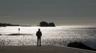 Mies seisoo meren rannalla.