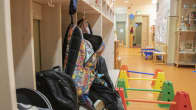Backpacks hanging on a rack at a daycare centre.