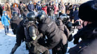 mellakkavarusteisiin pukeutuneet poliisit pidättävät mielenosoittajaa lumisessa kaupungissa