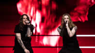 Kaksi Blind Channelin jäsentä laulaa mikrofoniin lavalla, takana voimakas punainen tausta. Molemmilla miehillä on pitkät hiukset ja mustat asut.
