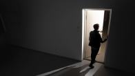 Henkilö seisoo avoimella ovella, josta tulee valoa pimeään huoneeseen.