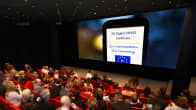 Elokuvateatterin yleisö katsoo valkokankaalla olevaa koronapassia.