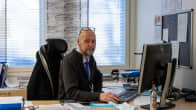 Kannonkosken kunnanjohtaja Sakari Varala istuu työhuoneessaan tietokoneen ääressä ja katsoo hymyillen kameraan silmälasit otsallaan.