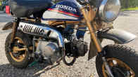 Honda Monkey (Z50J) -merkkinen mopedi, taustalla näkyy farkkuasuisen miehen jalat.