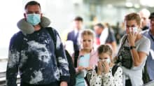Hengityssuojaimiin pukeutunut perhe Suvarnabhumin lentoasemalla Thaimaassa.
