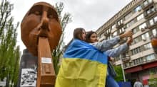 Ukrainalaisnuoret ottavat selfieitä patsaan edustalla.