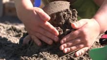 Lapsen kädet tekemässä hiekkakakkua