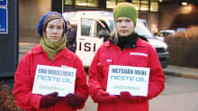 Kaksi Greenpeacen mielenosoittajaa Neste Oilin pääkonttorin ulkopuolella.