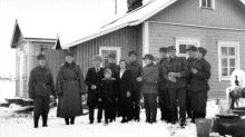 Sotilaita seisoo maalaistalon pihalla isäntäväen kanssa.