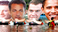 Mielenosoittajat kelluttavat vedessä suuria pahvisia kasvokuvia muun muassa Obamasta ja Medvedevistä.
