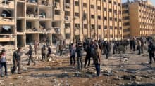 Ihmiset tutkivat pommi-iskun aiheuttamia tuhoja Aleppon yliopiston edustalla.