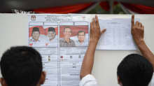 Vaalivirkailijat kiinnittävät ehdokkaita esittäviä julisteita seinään äänestyspaikalla Jakartassa 9. heinäkuuta 2014. 