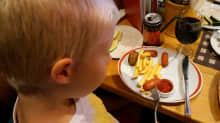 Poika syö lastenateriaa ravintolapöydässä