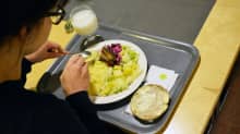 Nainen syö lounasta työpaikkaruokalassa.