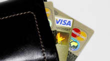 Kuvassa lompakko, joka pursuaa luottokortteja.