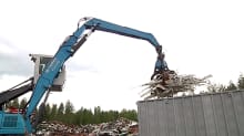 Kone nostaa metallijätettä kontista.