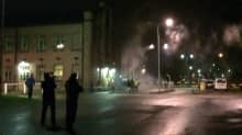 Poliiseja ja mielenosoittajia Hennalan entisen kasarmialueen portilla.