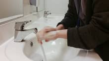 Henkilö pesee käsiään lavuaarissa. 