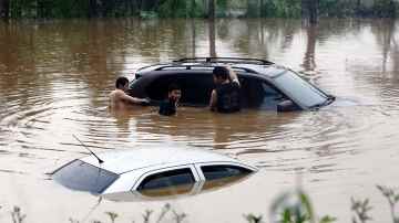 Nuoret yrittävät siirtää tulvan saartamaa autoaan Dongguanin kaupungissa Guangdongin maakunnassa Kiinassa 31. maaliskuuta 2014. 