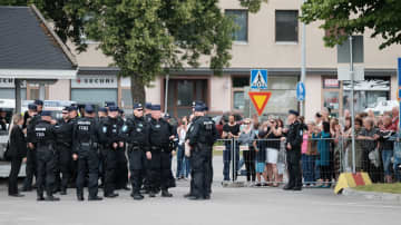 Joukko poliiseja seisoo kadulla väkijoukon edessä.