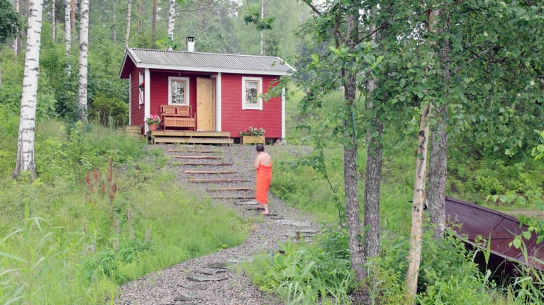 Nainen kävelee kesämökin pihalla.