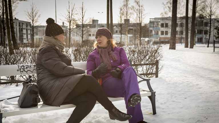 Äitimentori Tiina Tervonen ja perheenäiti Heini Mielonen juttelevat puiston penkillä.