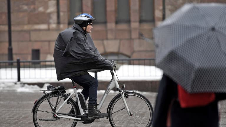 Polkupyöräilijä vesisateessa Helsingissä 13. maaliskuuta.