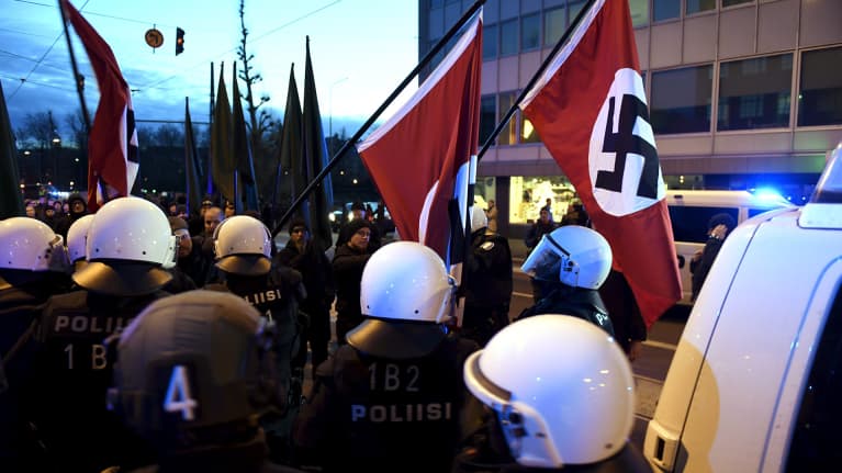 Poliisit poistivat hakaristiliput mielenosoittajilta.