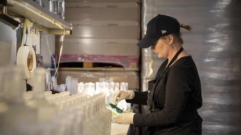 Kirsi Holopainen maalaa pullon etikettiä. 