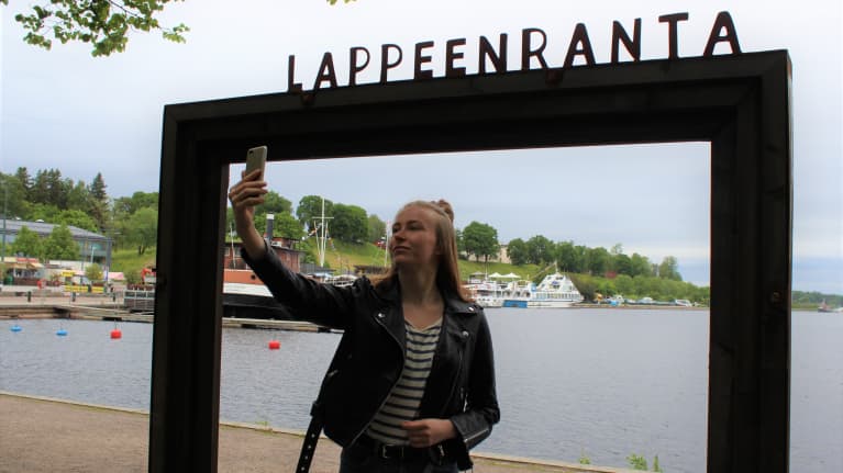 Hanna Muukkonen ottaa itsestään valokuvan Lappeenrannan maisemakehyksissä.