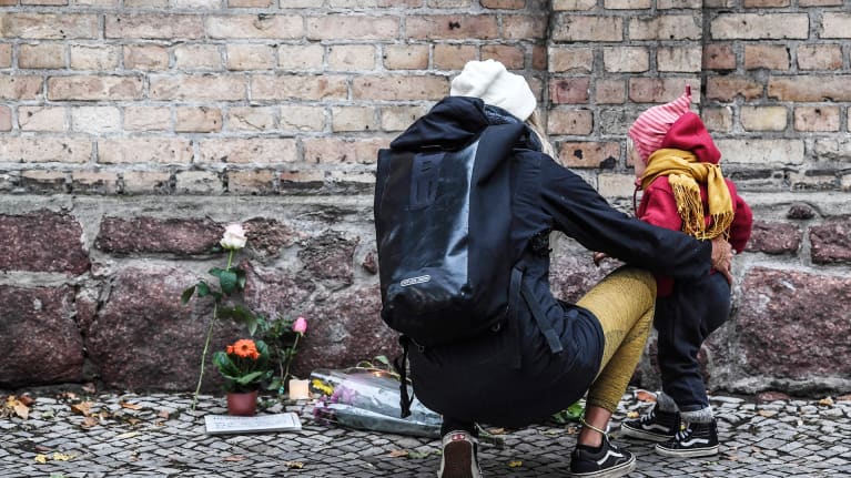 Nainen toi lapsensa kanssa kukkia synagogan edustalle 10. lokakuuta.