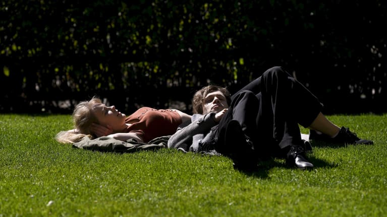 Ihmisiä nauttimassa lämpimästä säästä Helsingin Esplanadin puistossa lauantaipäivänä.