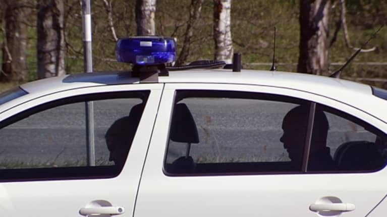 Mies istuu poliisiauton takapenkillä.