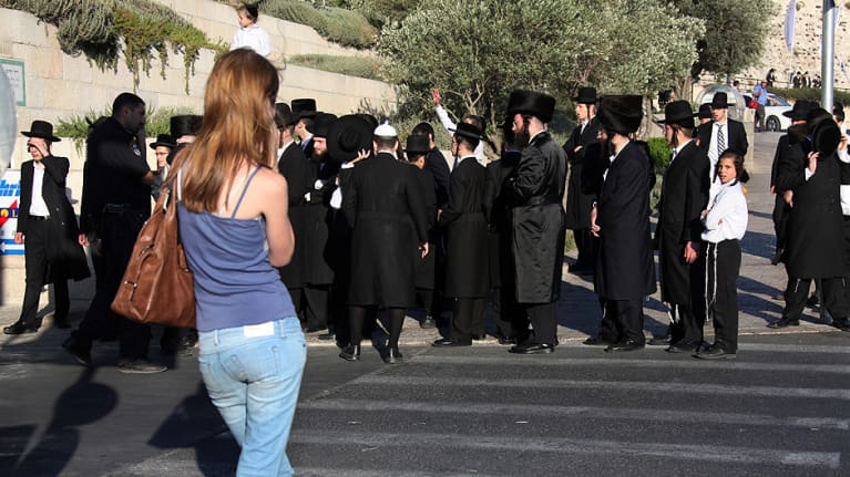 Nuori nainen ja joukko ortodoksijuutalaisia.