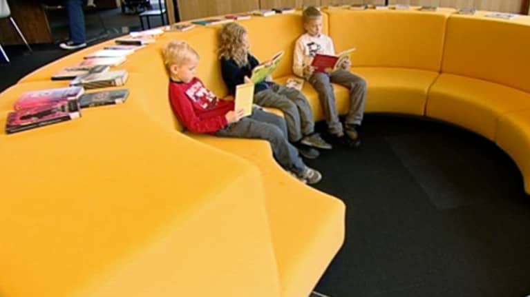 Lapsia lukemassa kirjston pyöreällä sohvalla