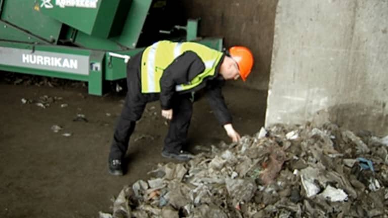 YTV:n työntekijä nostaa muovista jätepussia Ämmässuon kaatopaikalla.