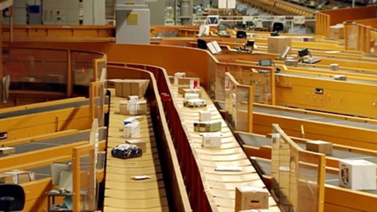 Paketteja kulkee hihnoja pitkin Postin lajittelukeskuksessa.