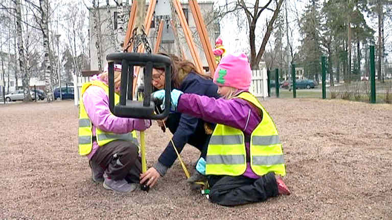 tytöt mittaavat keinun korkeutta.