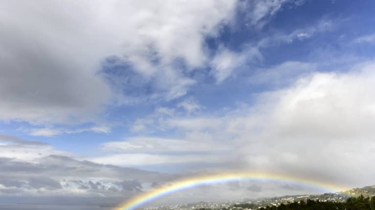 Sateenkaari kaupungin yllä järven rannassa.