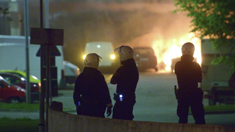 Poliisit katselevat palavaa autoa.