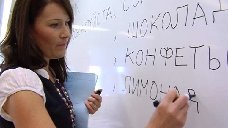 Opettaja kirjoittaa tussilla taululle kyyrillisiä kirjaimia