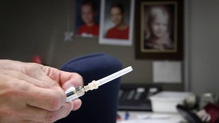 Hoitajaa pitää kädessään rokotusruiskua neuvolassa.